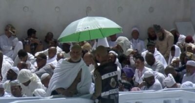 رجل أمن بالمسجد الحرام يحمي معتمراً من حرارة الشمس خلال خطبة أول جمعة برمضان